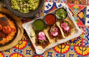 a table topped with plates of food and a bowl of guacamole